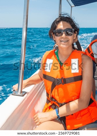 Young Hispanic Latin Mexican girl travels by boat to see the arch of Cabo San Lucas on her summer vacation on a beautiful sunny day. Mexico