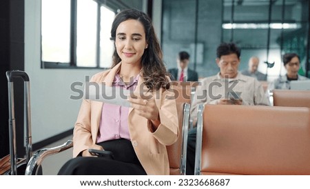 Young hispanic latin woman passenger checking depature boarding pass while sitting on chair in terminal departure gate waiting flight at international airport