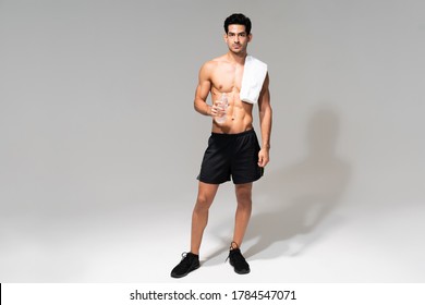 Young Hispanic Male Athlete With Towel On Shoulder Holding Bottle Of Water