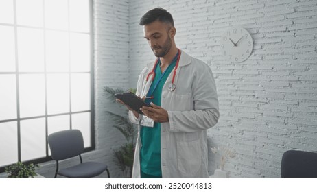 Young hispanic male doctor holding a tablet in a brightly lit clinic's waiting room, wearing a white coat and stethoscope, displaying a serious expression as he focuses on the screen. - Powered by Shutterstock