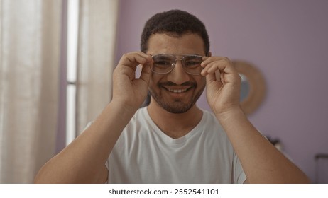 Young hispanic man adjusting glasses while smiling in a well-lit living room. - Powered by Shutterstock