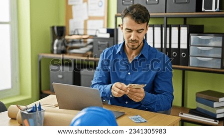 Young hispanic man architect having video call counting mexican pesos at office