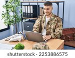 Young hispanic man army soldier using laptop sitting on table at office