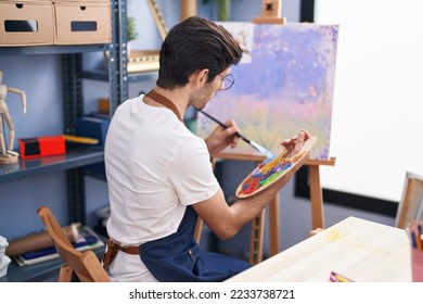 Young hispanic man artist sitting back view drawing at art studio