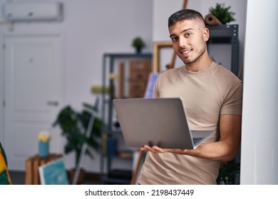 Young hispanic man artist smiling confident using laptop at art studio - Shutterstock ID 2198437449