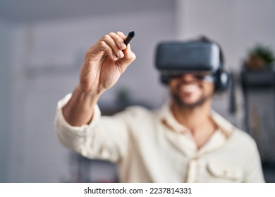 Young hispanic man artist using virtual reality glasses drawing at art studio - Powered by Shutterstock