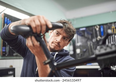 Young hispanic man assembling a bicycle saddle in his bike workshop as part of a maintenance service. Real people at work.Composition with selective focus and copy space. - Powered by Shutterstock