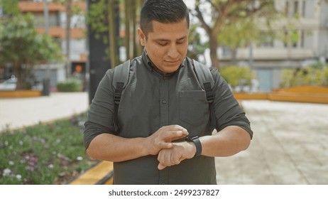 Young hispanic man with backpack checking smartwatch in city park - Powered by Shutterstock