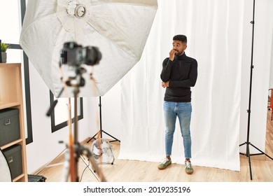 Young Hispanic Man With Beard Posing As Model At Photography Studio Looking Stressed And Nervous With Hands On Mouth Biting Nails. Anxiety Problem. 