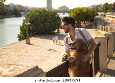 Young Hispanic man with beard, sunglasses and white shirt, leaning out with his dog leaning on a railing in funny attitude. Concept animals, dogs, love, pets, golden.