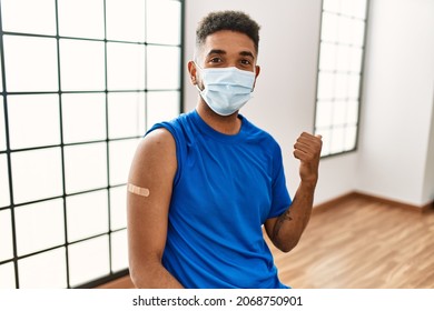 Young Hispanic Man With Beard Wearing Safety Mask Getting Vaccine Pointing Thumb Up To The Side Smiling Happy With Open Mouth 