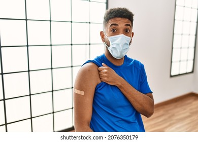 Young Hispanic Man With Beard Wearing Safety Mask Getting Vaccine Scared And Amazed With Open Mouth For Surprise, Disbelief Face 