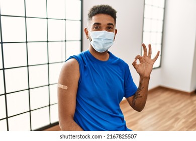 Young Hispanic Man With Beard Wearing Safety Mask Getting Vaccine Doing Ok Sign With Fingers, Smiling Friendly Gesturing Excellent Symbol 