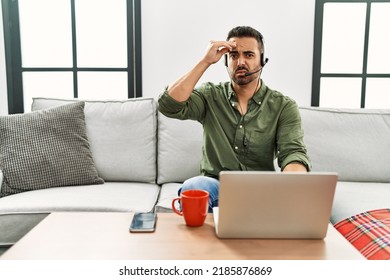 Young Hispanic Man With Beard Wearing Call Center Agent Headset Working From Home Worried And Stressed About A Problem With Hand On Forehead, Nervous And Anxious For Crisis 