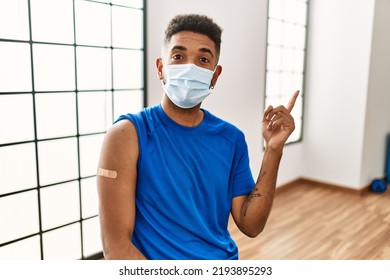 Young Hispanic Man With Beard Wearing Safety Mask Getting Vaccine Smiling Happy Pointing With Hand And Finger To The Side 