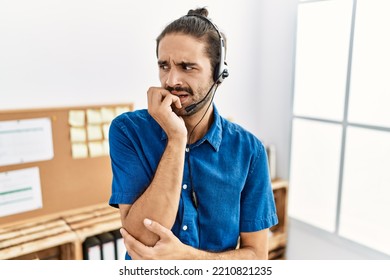 Young Hispanic Man With Beard Wearing Call Center Agent Headset At The Office Looking Stressed And Nervous With Hands On Mouth Biting Nails. Anxiety Problem. 