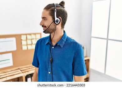 Young Hispanic Man With Beard Wearing Call Center Agent Headset At The Office Looking To Side, Relax Profile Pose With Natural Face With Confident Smile. 