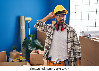 Young Hispanic Man With Beard Working At Home Renovation Confuse And Wondering About Question. Uncertain With Doubt, Thinking With Hand On Head. Pensive Concept. 