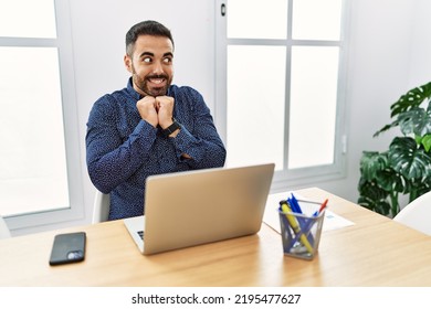 Young Hispanic Man With Beard Working At The Office With Laptop Laughing Nervous And Excited With Hands On Chin Looking To The Side 