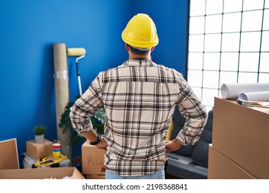 Young Hispanic Man With Beard Working At Home Renovation Standing Backwards Looking Away With Arms On Body 