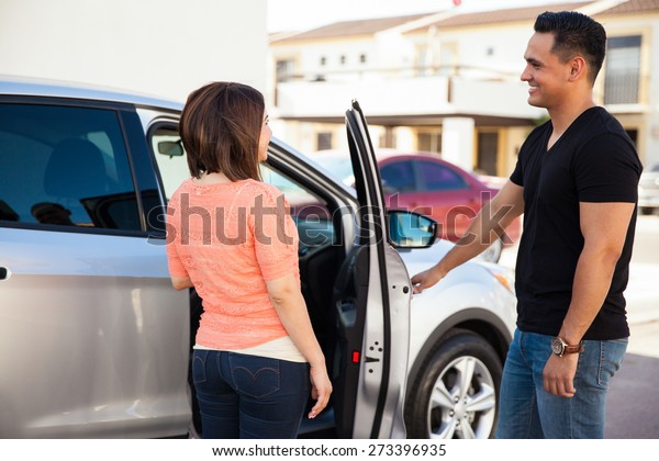Young Hispanic man being a gentleman and opening the\
car door for her date
