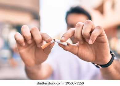 Young hispanic man breaking cigarette with hands walking at the city. - Shutterstock ID 1950373150