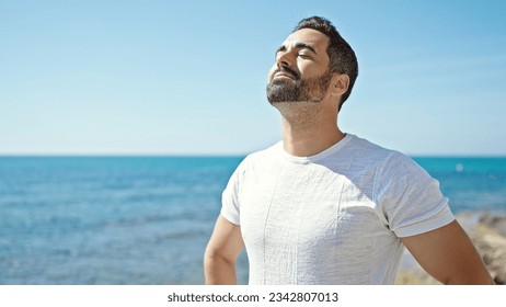 Young hispanic man breathing with closed eyes at seaside - Powered by Shutterstock