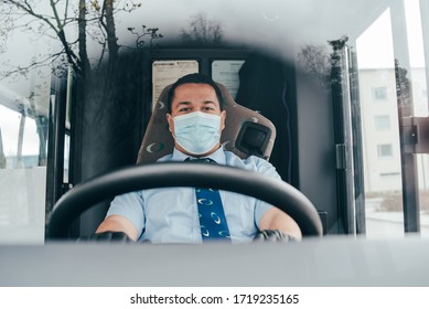 Young Hispanic Man Bus Driver  In A Protective Mask And Black Gloves. Prevent The Spread Of Coronavirus. Young Hispanic Bus Driver Wearing A Protective Mask And Looks At Client. Quarantine. Covid 19.