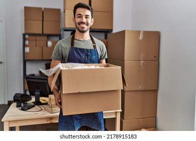 Young hispanic man business worker holding package at storehouse - Shutterstock ID 2178915183