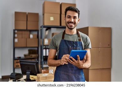 Hombre joven hispano trabajador de negocios usando touchpad en un almacén