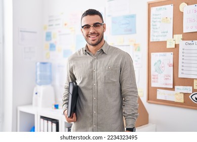 Young hispanic man business worker smiling confident holding binder at office - Powered by Shutterstock