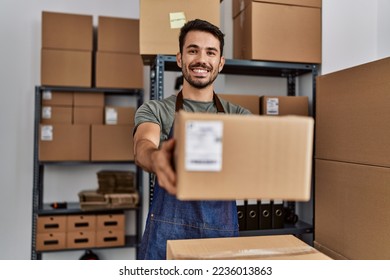 Young hispanic man business worker holding package at storehouse - Shutterstock ID 2236013863