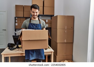 Young hispanic man business worker holding package at storehouse - Shutterstock ID 2254032005