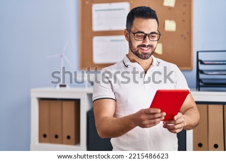 Young hispanic man business worker using touchpad at office