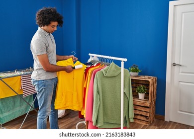 Young Hispanic Man Cleaning Clothes Using Pet Hair Roller At Laundry Room