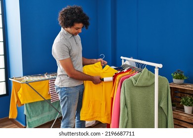 Young Hispanic Man Cleaning Clothes Using Pet Hair Roller At Laundry Room