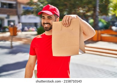 Young Hispanic Man Courier Holding Take Away Paper Bag With Food At Street