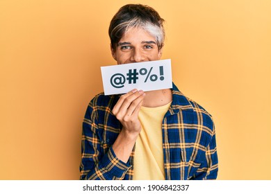 Young Hispanic Man Covering Mouth With Insult Message Paper Looking Positive And Happy Standing And Smiling With A Confident Smile Showing Teeth 