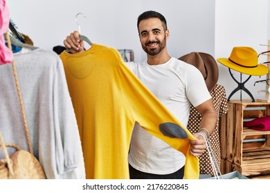 Young Hispanic Man Customer Choosing Clothes Shopping At Clothing Store