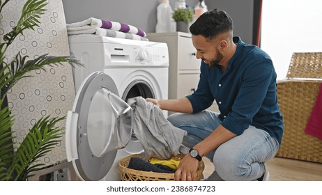 Young hispanic man doing laundry with washing machine at laundry room - Powered by Shutterstock