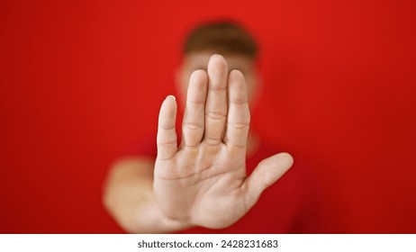 Young hispanic man doing stop gesture with hand over isolated red background