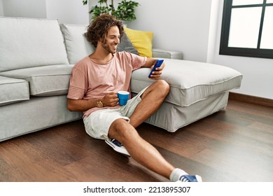 Young hispanic man drinking coffee and using smartphone sitting on the floor at home. - Powered by Shutterstock