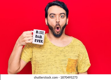 Young Hispanic Man Drinking Mug Of Coffe With Best Dad Ever Message Scared And Amazed With Open Mouth For Surprise, Disbelief Face 