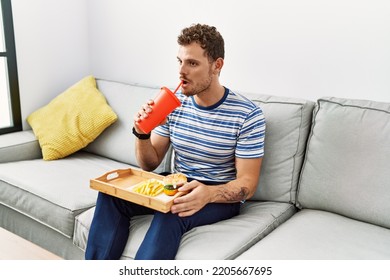 Young Hispanic Man Drinking Soda At Home