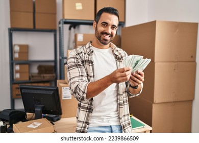 Young hispanic man ecommerce business worker counting dollars at office