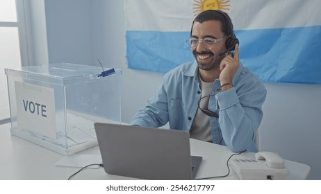 Young hispanic man in electoral college room indoors in argentina, smiling and wearing headset, next to voting ballot box and laptop, with argentinian flag in background - Powered by Shutterstock