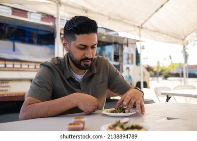 Young Hispanic Man Enjoying A Carnitas Taco Outside