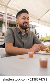 Young Hispanic Man Enjoying A Carnitas Taco Outside