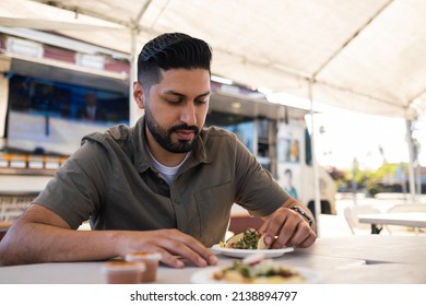 Young Hispanic Man Enjoying A Carnitas Taco Outside