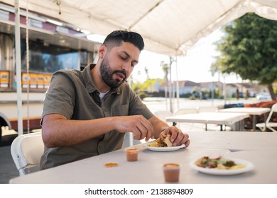 Young Hispanic Man Enjoying A Carnitas Taco Outside